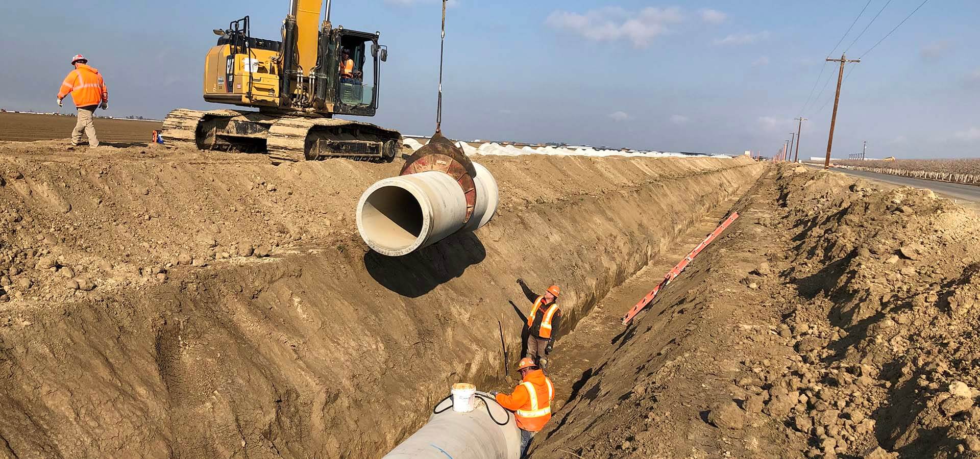 Site engineers laying utility pipework in a trench